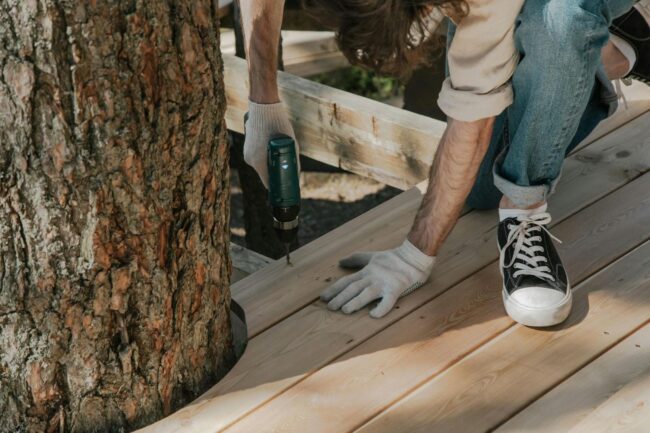 man drilling on wooden plank